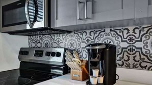 A kitchen with a stove, microwave, coffee maker, and a knife block.