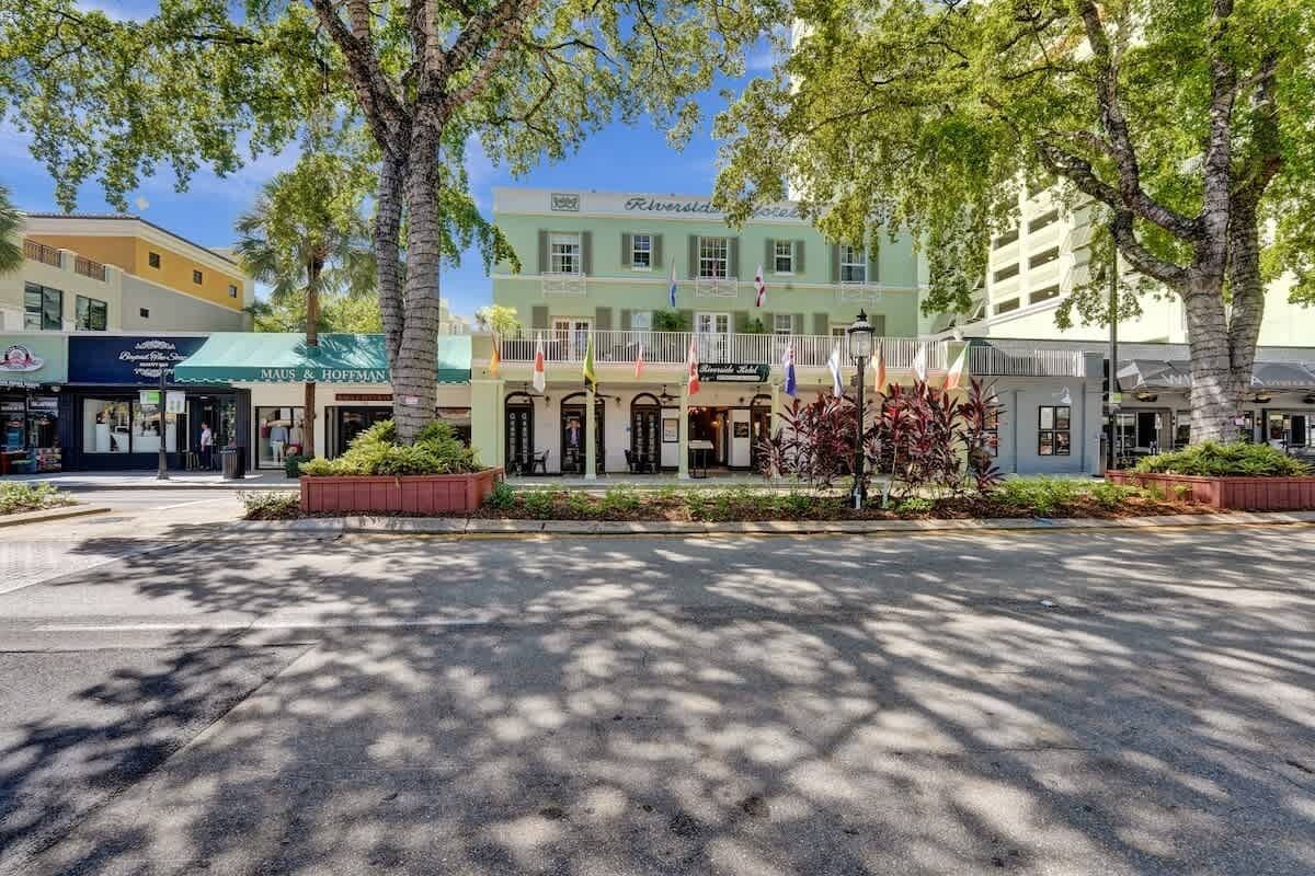 Ein Hotel mit grüner Fassade, mehreren Flaggen und einem zentralen Eingang mit einem überdachten Vorbau.