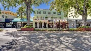 A hotel with a green facade, multiple flags, and a central entrance with a covered porch.