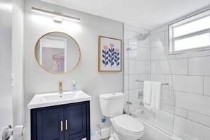 Un bagno moderno con un lavandino bianco, mobili scuri, un water e una vasca da bagno.