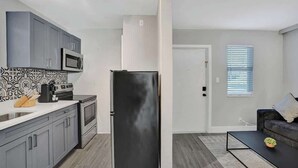 A modern kitchen with grey cabinets, a black refrigerator, and a patterned backsplash.