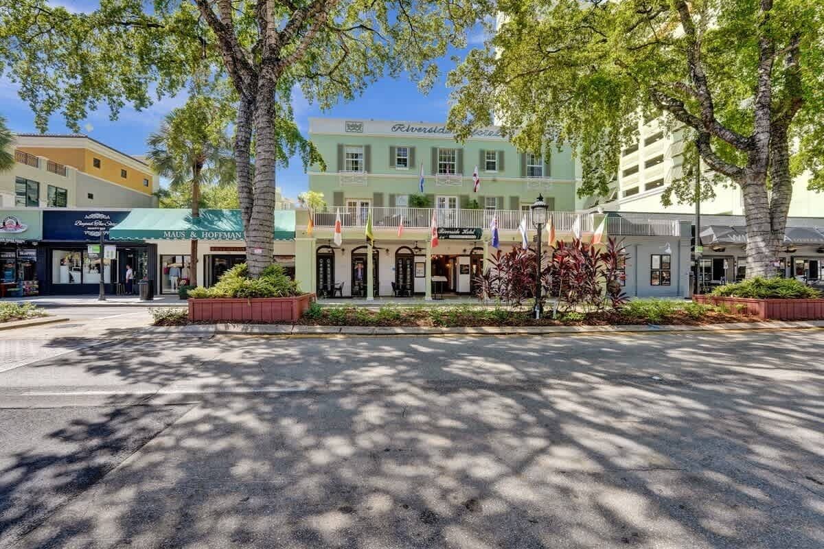 A hotel with a green facade, multiple flags, and a central entrance with a covered porch.