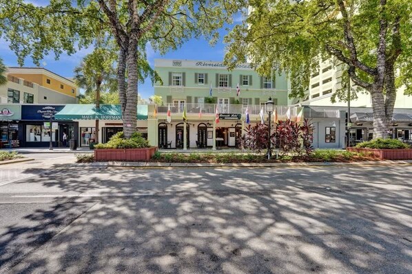 A hotel with a green facade, multiple flags, and a central entrance with a covered porch.
