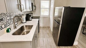 Una cocina moderna con electrodomésticos de acero inoxidable, un lavamanos doble y un ventanal que proporciona luz natural.