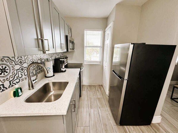 A modern kitchen with stainless steel appliances, a double sink, and a window providing natural light.