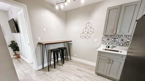 Una cocina moderna con encimera gris, refrigerador de acero inoxidable y un adorno hexagonal en la pared.