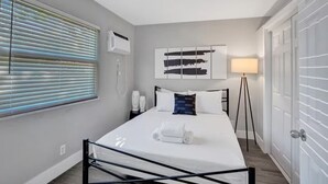 Un dormitorio moderno con cama, mesitas de noche, lámpara y ventana con persianas.
