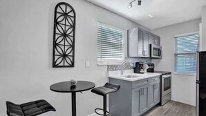 Una cocina moderna con armarios grises, una encimera negra y un taburete negro.