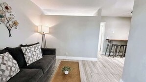 A living room with a sofa, a coffee table with a plant, and a dining area with a table and chairs.