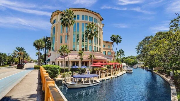 A hotel with a waterfront canal, a boat dock, and outdoor seating with umbrellas.