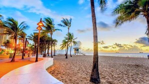 A beach with palm trees, a lifeguard tower, and a walkway.