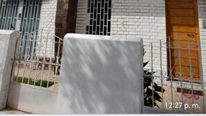 A two-story house with a white exterior, a wooden door, and a metal gate. - Valícha B&B breakfast (Cusco)