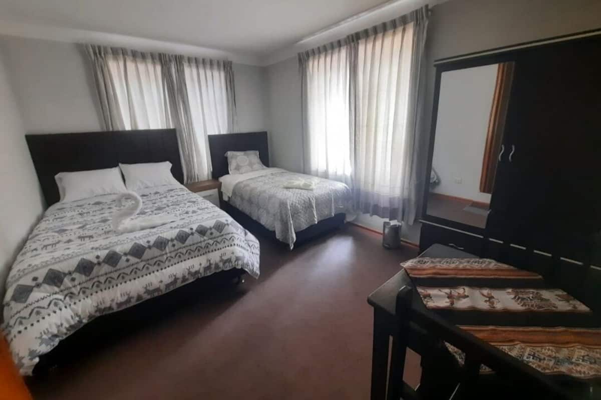 A hotel room with two beds, a desk, and a wardrobe.