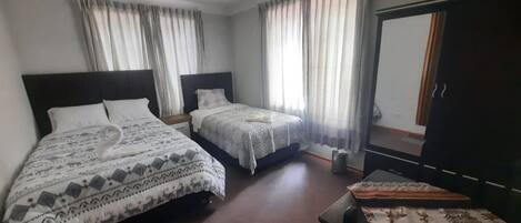 A hotel room with two beds, a desk, and a wardrobe.