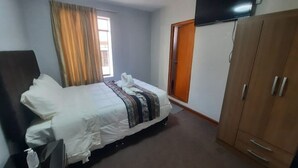 A hotel room with a bed, a wardrobe, a television mounted on the wall, and a window with curtains. - Valícha B&B breakfast (Cusco)