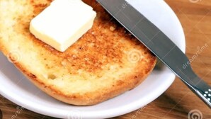 Toast with butter and a knife on a plate, a glass of orange juice, and a small dish of butter. - Valícha B&B breakfast (Cusco)