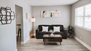 Un salon avec un canapé marron foncé, une table basse et un tableau accroché au mur.