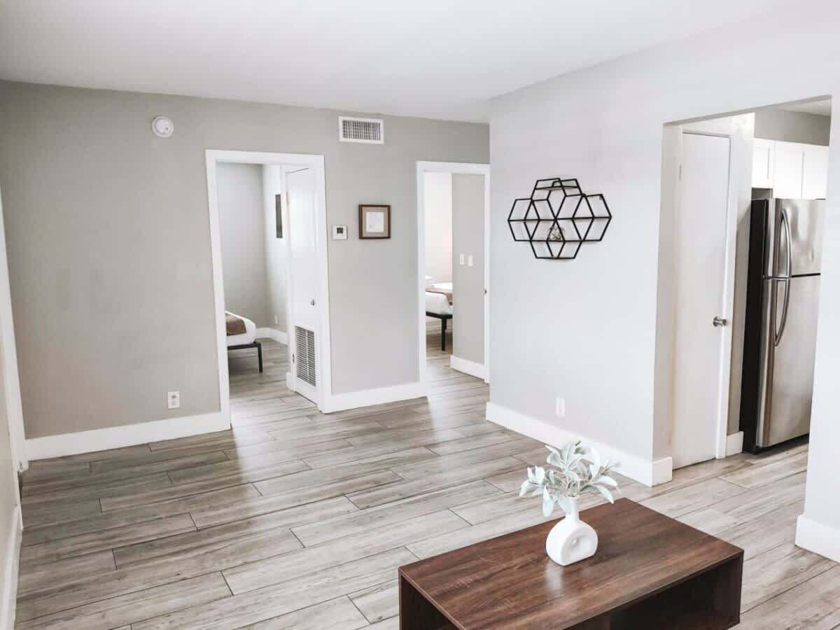 A spacious living area with a wooden floor, a coffee table with a vase, and a hexagonal wall decoration.