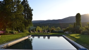A rectangular swimming pool with a view of a hilly landscape and trees in the background. - Country House With Private Pool (Toscane)