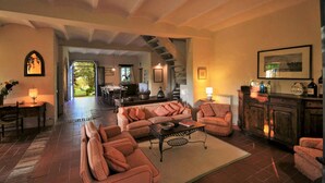 A spacious living room with a fireplace, a dining area, and a kitchen visible through an open archway. - Country House With Private Pool (Toscane)