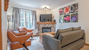 Una sala de estar con chimenea de piedra, un sofá y un televisor.