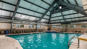 Ein Hallenbad mit klarem Wasser, einer Dachkonstruktion und mehreren Panoramafenstern.