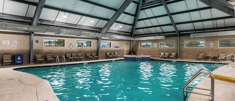 An indoor swimming pool with clear water, a roof structure, and multiple viewing windows.