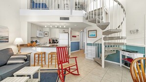 Amplia sala de estar con cocina, comedor y una escalera que conduce a un nivel superior.