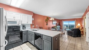 A modern kitchen with a large island, white cabinets, and a view to the outside. - Gulf Shores Plantation-Palms 6512 (Gulf Shores)