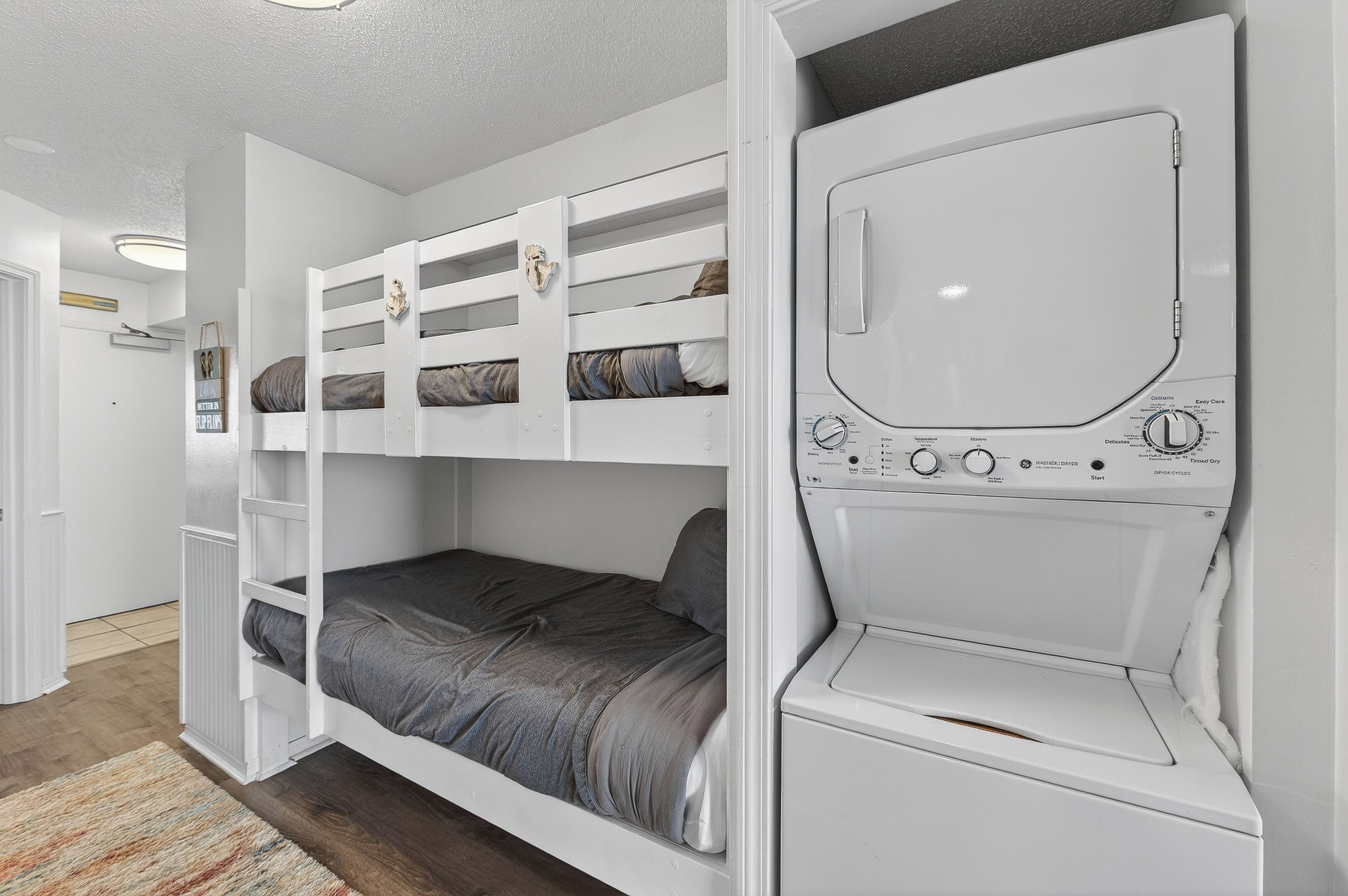 A bunk bed with a washing machine integrated into the wall, a radiator, and a door leading to another room.