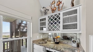 A kitchen with a granite countertop, white cabinetry, and a view of the beach.