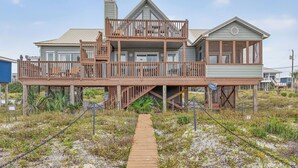 A beachfront house with a wooden deck, a balcony, and a covered area.