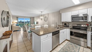 A modern kitchen with white cabinets, stainless steel appliances, and a large island with a dishwasher.