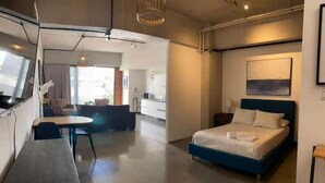 Ein modernes Hotelzimmer mit einem großen Bett, einem Essbereich und einer Küchenzeile.