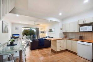 A modern kitchen with a dining area, a TV, and a view of the outdoors.