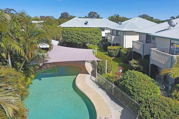 A residential property with a swimming pool, a covered patio, and a house with satellite dishes.