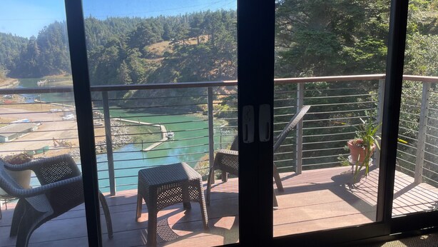 A balcony with a view of a river and forested hills. - Mendocino Coast Hideaway (Albion)