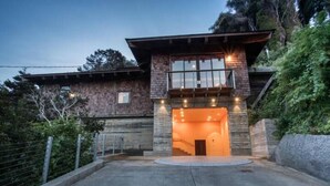A modern house with a prominent entrance, a balcony, and a well-lit interior. - Mendocino Coast Hideaway (Albion)