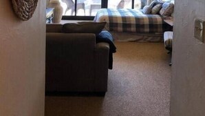A hotel room with a large bed, a sofa, and a view of the outdoors through large windows. - Mendocino Coast Hideaway (Albion)