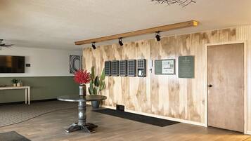 A reception area with a wooden wall, a reception desk, a plant, and a ceiling fan.