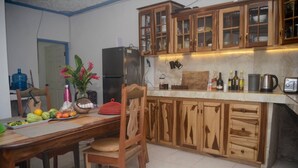 Una cocina con armarios de madera, encimera de mármol y un comedor con una mesa dispuesta para dos personas.