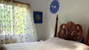 Un dormitorio con cama de madera, cortinas florales, decoración azul en la pared y alfombra verde.