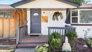 A house with a grey door, a porch with a bench, and a mailbox with the number 6758.