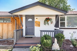A house with a grey door, a porch with a bench, and a mailbox with the number 6758.