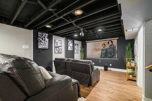 Ein Raum mit Ledersofas, einer Projektionsleinwand und Filmplakaten an der Wand.