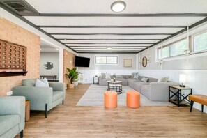 A modern living room with a sectional sofa, a coffee table, and a TV mounted on a brick wall.
