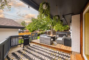Un patio techado al aire libre con una parrilla, zona de estar y vistas al jardín trasero.
