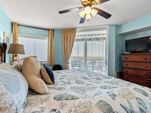 A bedroom with a bed, a ceiling fan, a television, and a view of the outdoors. - Beautiful 12th Floor Oceanfront Get Away in North Myrtle Beach (North Myrtle Beach)