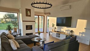 Un salon moderne avec un grand canapé d’angle, un téléviseur à écran plat et une cheminée.