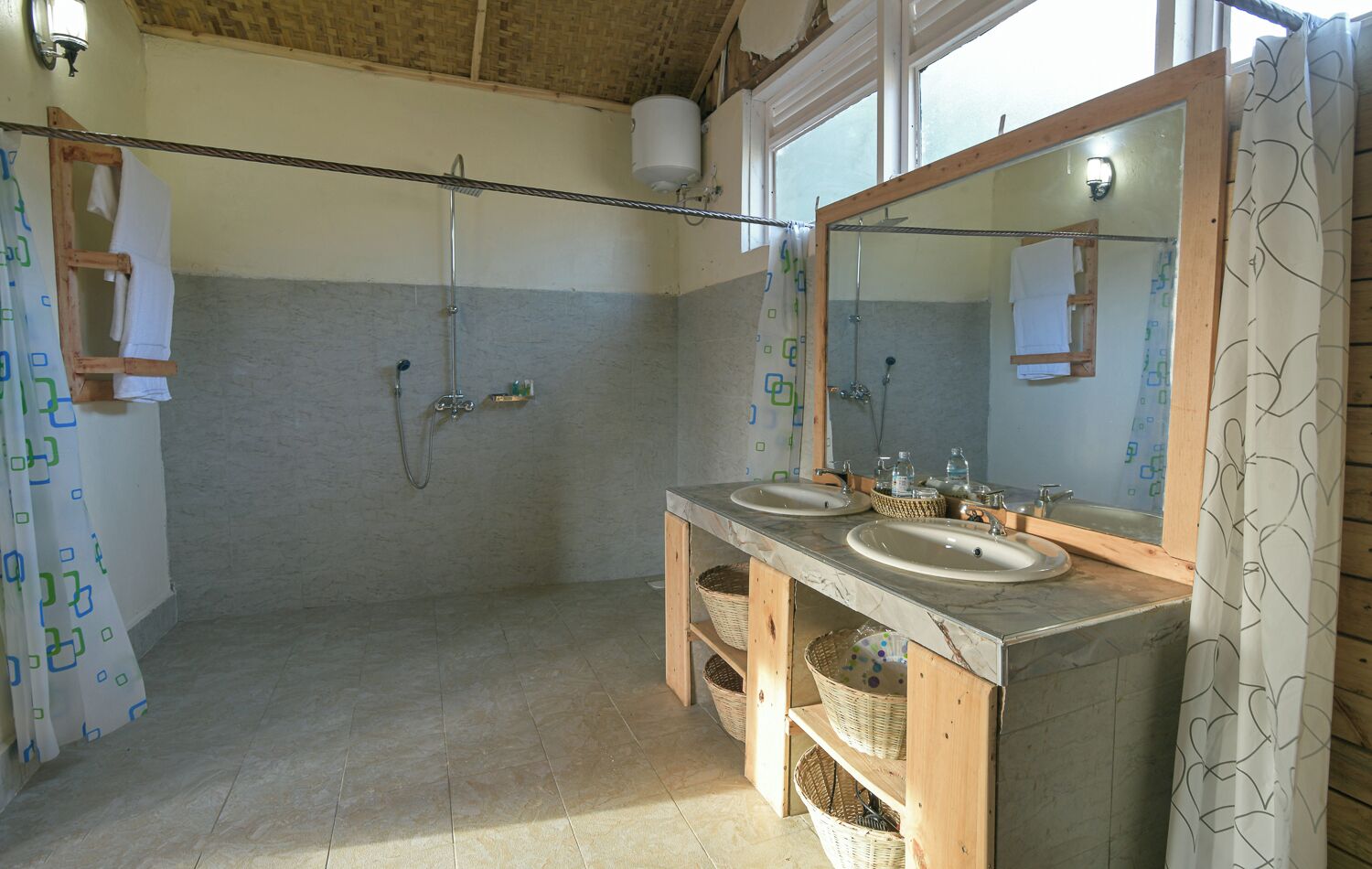 Un baño con dos lavamanos, ducha y espejo.